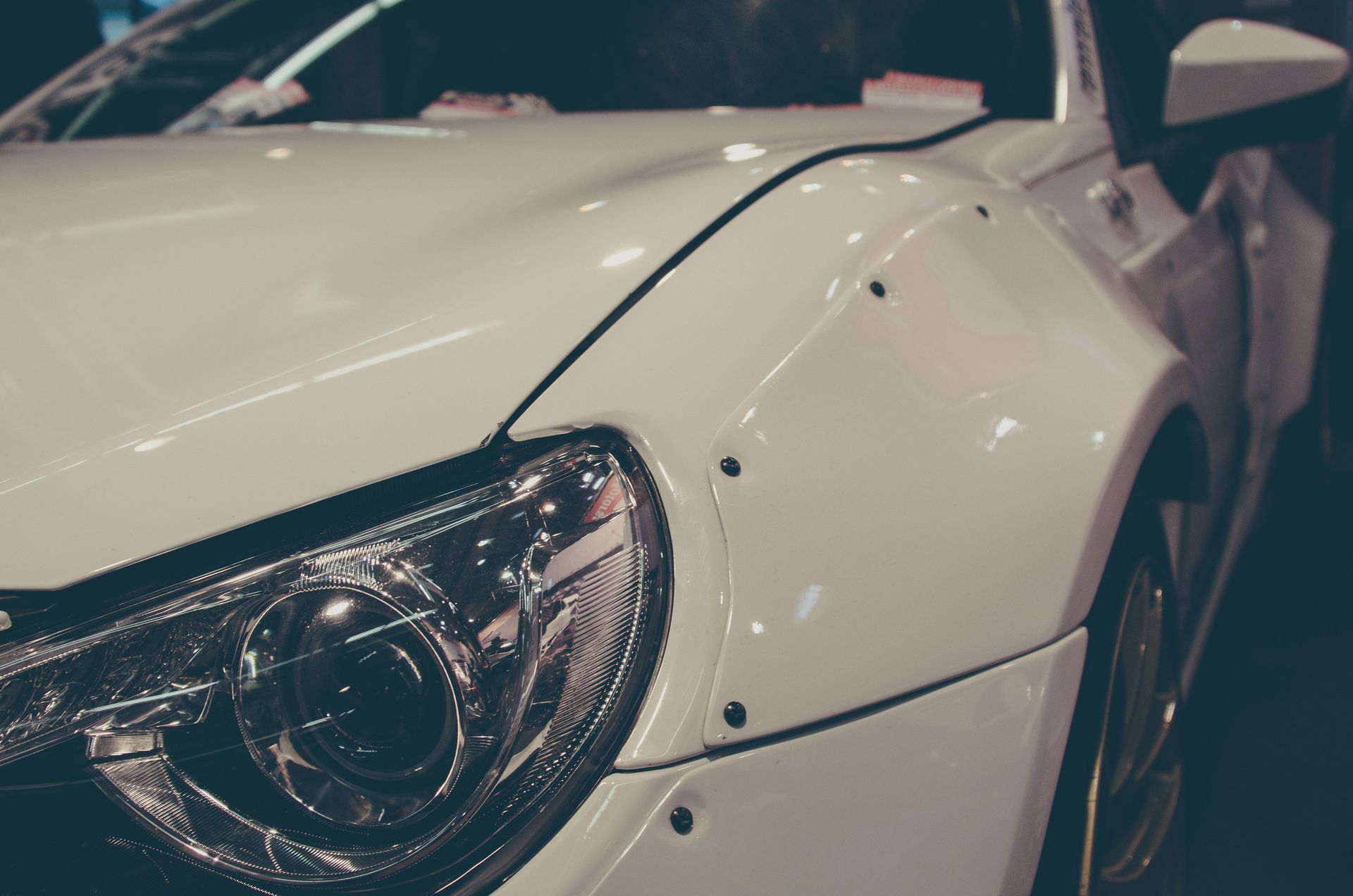 Detailed view of a white sports car showcasing its headlight and fender at an auto show in Essen, Germany.