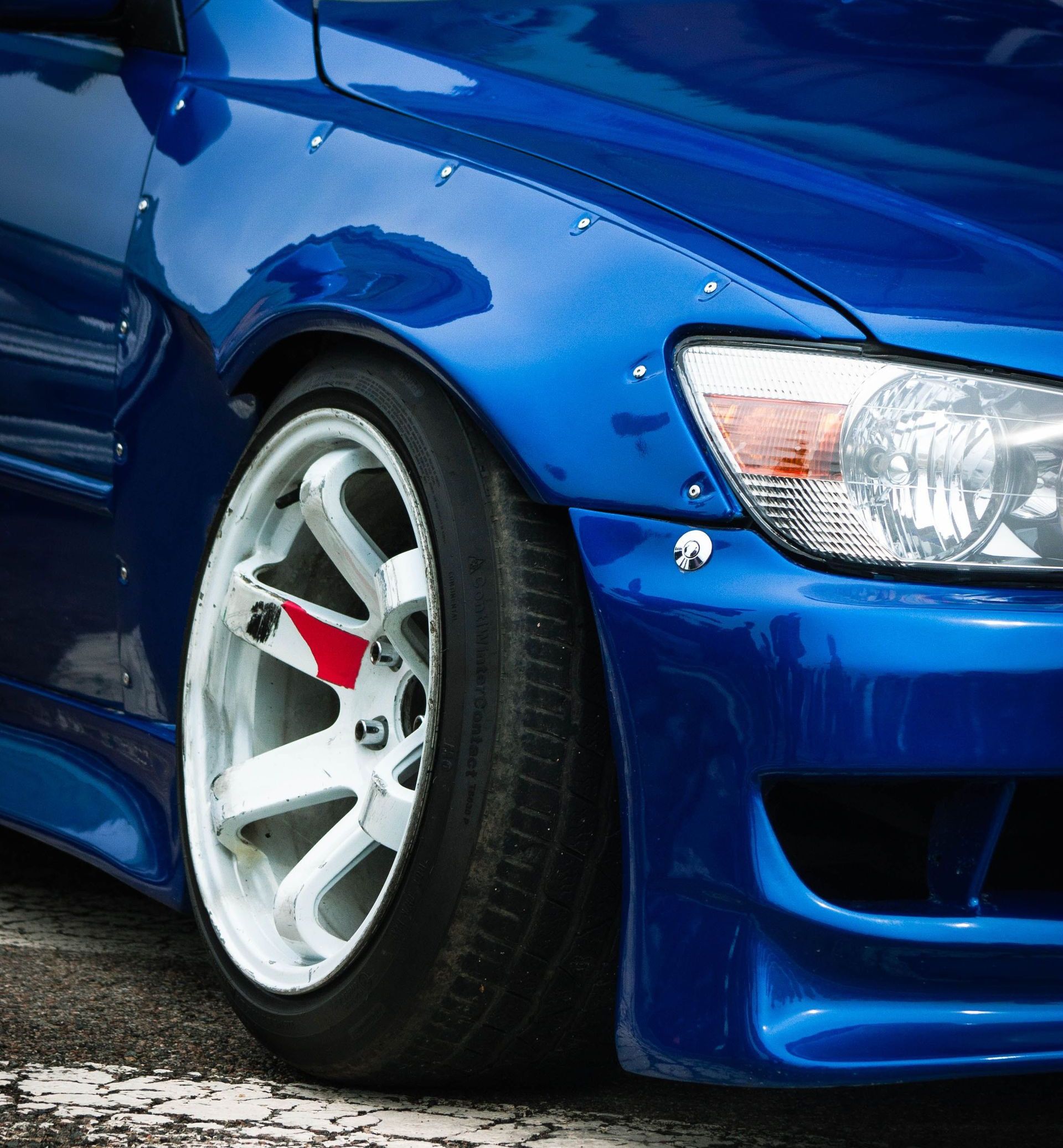 Close-up of a blue custom sports car featuring white alloy wheels, parked in Almaty, Kazakhstan.